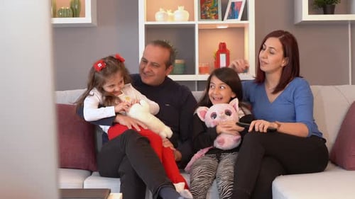 Smiling Family Watching TV on Sofa
