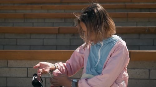 Petite fille enfant assise sur l'herbe dans le parc à la recherche d'une montre intelligente et met des Airpods, montre intelligente pour