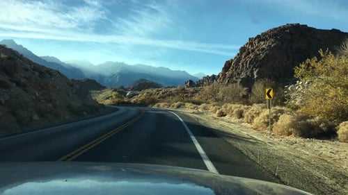 POV view out a car window of a rocky desert landscape.