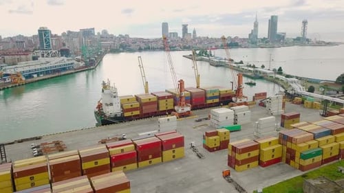 Ship view from a drone. Unloading of containers by a crew and a crane in port
