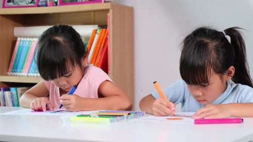 Two Young Girls Coloring Together Indoors