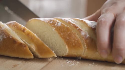 Closeup View of Slicing Bread on Wooden Cutting Board.