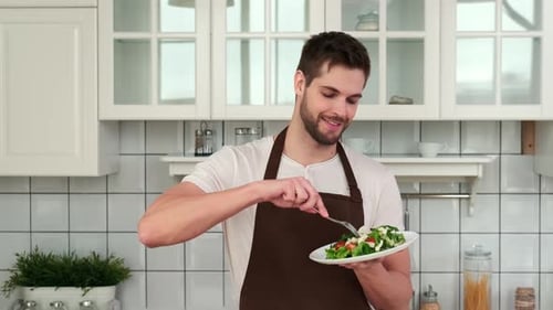 Young Adult Eating Salad in Bright Kitchen
