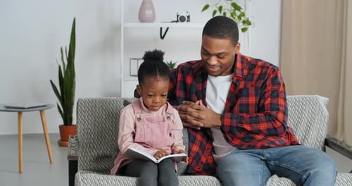 Father and Daughter Reading Together on Sofa