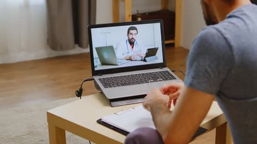 Man consults doctor through video call on laptop