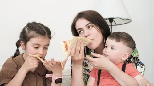 Mother and Children Eating Pizza at Home