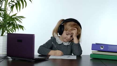 Little Girl Wearing Headphones Studying at Desk