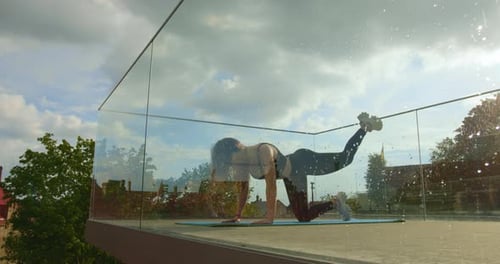 A Sporty Girl is Doing a Leg Lift While Kneeling