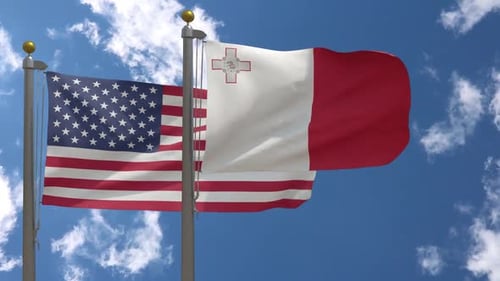 US and Malta Flags Waving in Wind Against Blue Sky