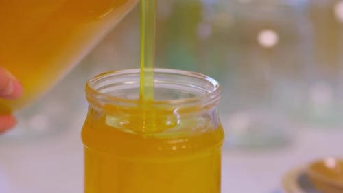 Golden Honey Pouring into Glass Jar