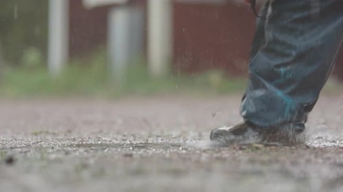 Child Splashing in Puddle During Rainstorm