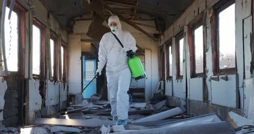 Virologe in Schutzkostüm und Atemschutzmaske desinfiziert Oberflächen