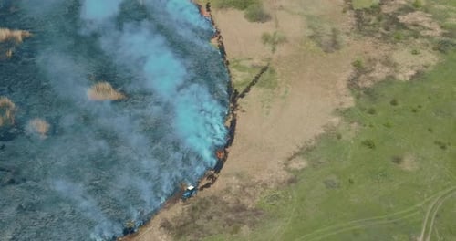 Quadcopter Flies Over a Burning Field Extinguishing a Fire