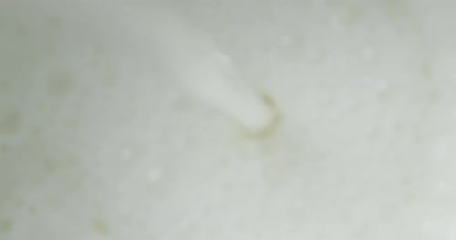 Milk Pouring Into Glass with Air Bubbles.