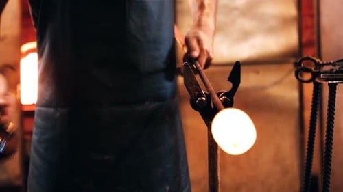 Mid section of glassblower forming and shaping a molten glass