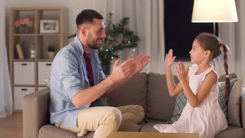 Smiling Man and Girl Playing Clapping Game on Couch