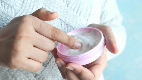 Woman Takes Cream from Jar for Skincare