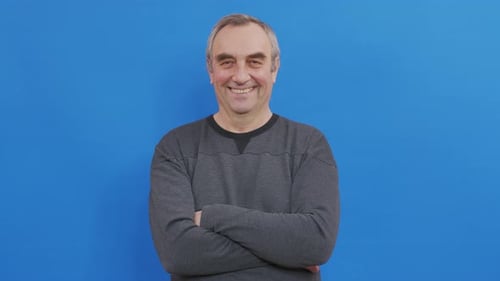 Smiling Man with Arms Crossed Stands Indoors
