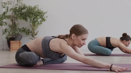 Women Practicing Yoga in Bright Studio