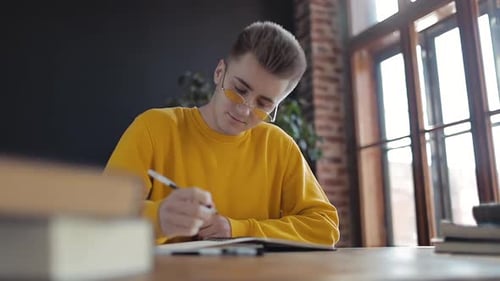 Young Adult Studying and Writing in Notebook