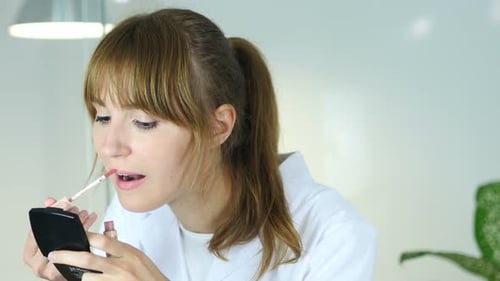 Woman Applying Lip Gloss with Handheld Mirror