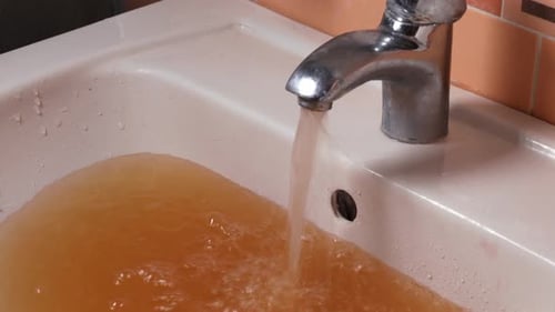Dirty Water Flowing from Faucet into Sink