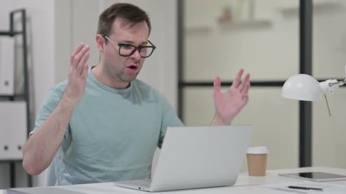 Frustrated Man Working on Laptop in Office