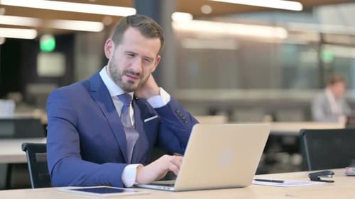 Businessman Working on Laptop, Experiencing Neck Pain