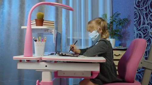 Child Wearing Mask Using Laptop at Desk