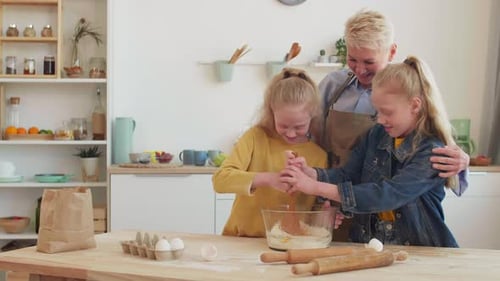 Two Blonde Girls Baking With an Adult in Kitchen