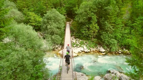 Aerial view of a couple crossing wooden bridge on bicycles.