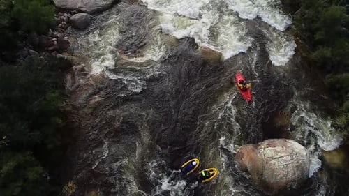 Aerial footage of white water kayaks paddling in the white water rapids on a freestone stream in the
