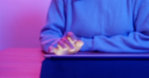 Hands Using Tablet Device in Pink and Blue Light