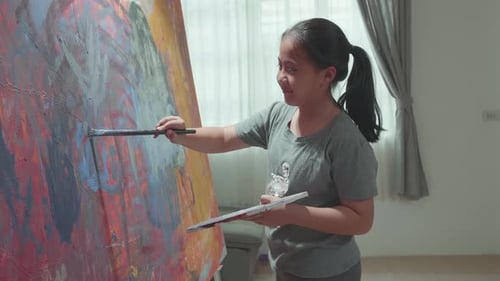 Young Girl Painting Abstract Art on Canvas Indoors