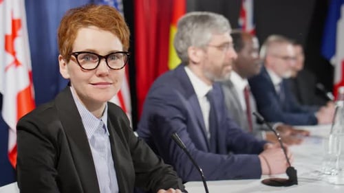 Adults at Press Conference Sitting Behind Microphones