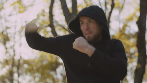 Man in Hoodie Boxing in Wooded Area