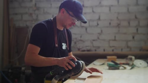 Carpentry Works Man Worker in Protective Glasses Grinding the Surface of a Wooden Detail