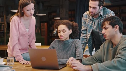 Young Adults Collaborating on Laptop in Urban Workplace
