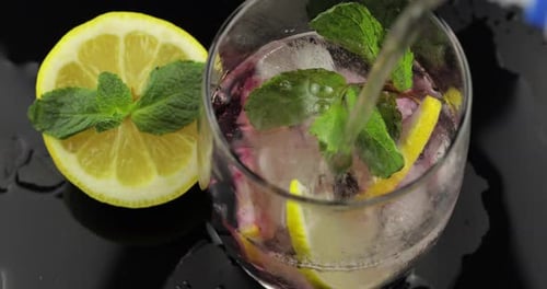 Pouring Drink Into a Glass With Lemon and Mint