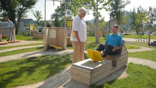 Adults Exercising on Outdoor Fitness Equipment on Sunny Day