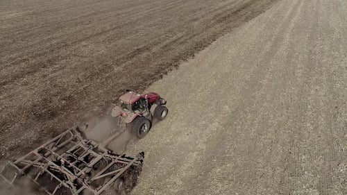 Un agriculteur en tracteur prépare la terre avec un cultivateur de semis