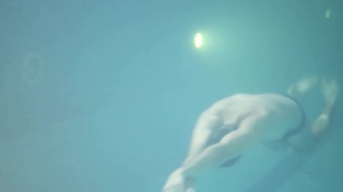 Man Swimming Underwater in Blue Pool