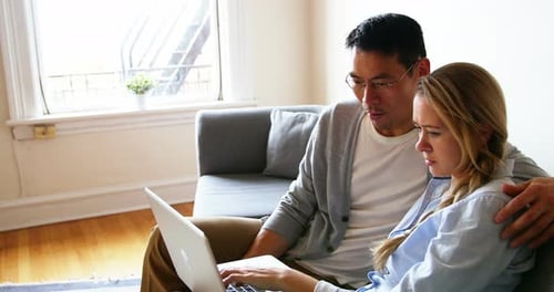 Couple Relaxing on Couch Using Laptop Together