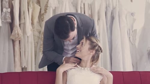 Affectionate Groom Kisses Bride in Bridal Shop