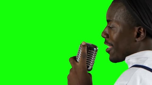 Hombre joven afroamericano, vista desde atrás acercándose al micrófono cantando en una grabación