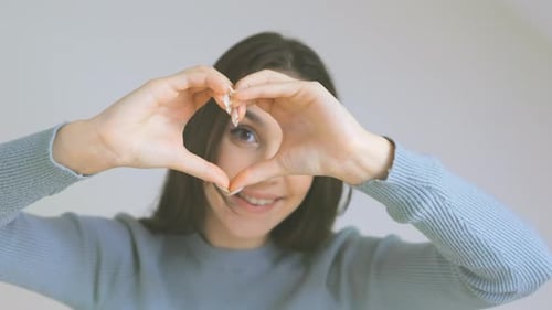 Woman Makes Heart Shape with Hands Smiling