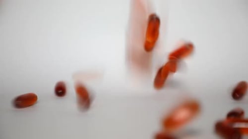 Close Up of Falling Liquid Capsules of Omega or Fish Oil on White Background
