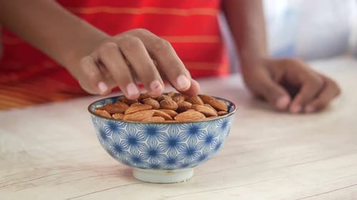 Hand Picking Almonds from Decorative Bowl