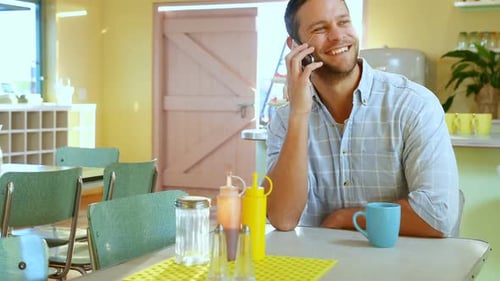 Smiling Man Talking on Phone in Cafe