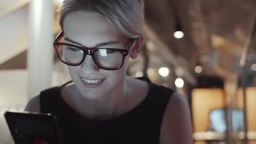 Woman Smiling Using Phone Indoors at Night